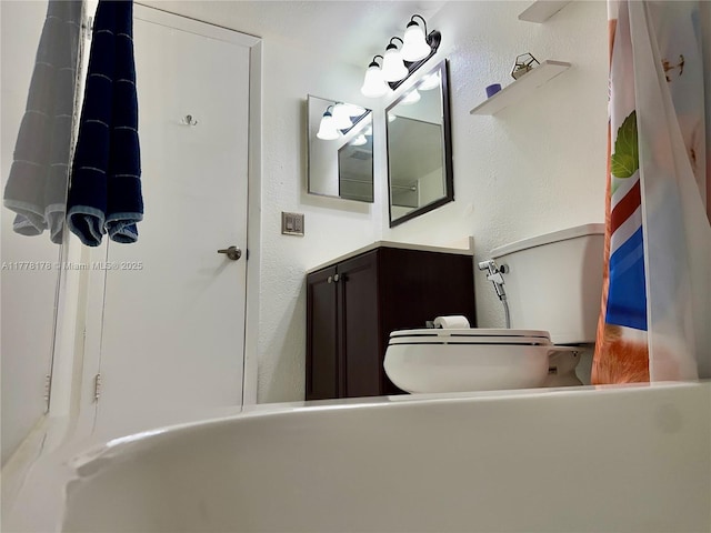 bathroom with a textured wall, vanity, and toilet