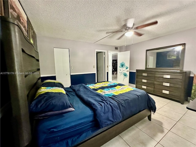 bedroom featuring light tile patterned floors, visible vents, a textured ceiling, and ceiling fan