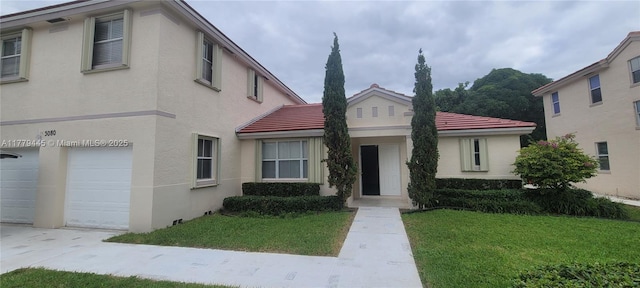 view of front of house featuring a garage, stucco siding, a tile roof, and a front yard