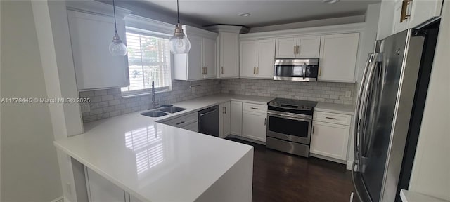 kitchen with a sink, light countertops, a peninsula, white cabinetry, and stainless steel appliances