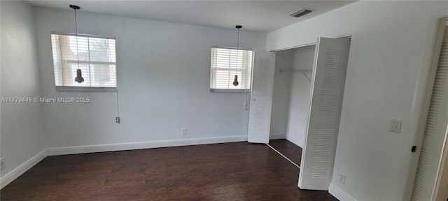 unfurnished bedroom featuring a closet, baseboards, dark wood finished floors, and visible vents