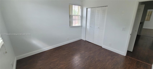 unfurnished bedroom featuring a closet, baseboards, and dark wood finished floors