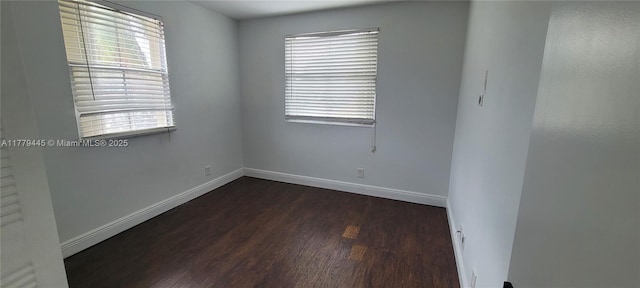 spare room with dark wood-style flooring and baseboards