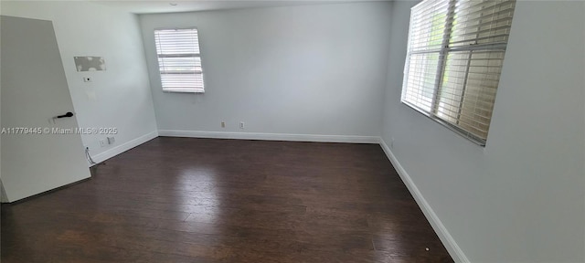 unfurnished room with baseboards and dark wood-style floors