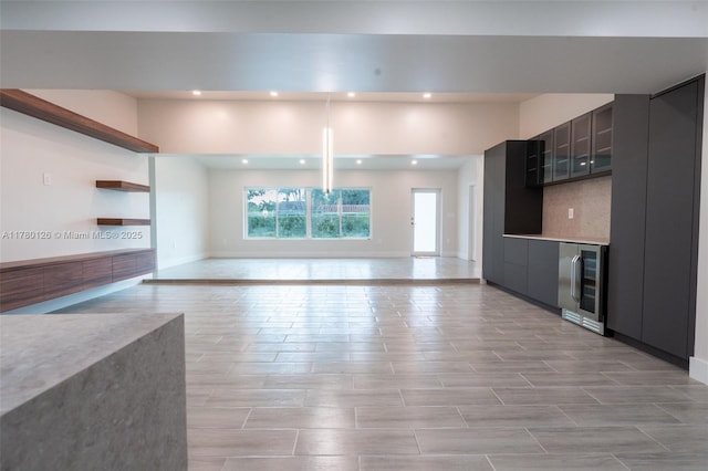 unfurnished living room featuring recessed lighting, beverage cooler, and baseboards