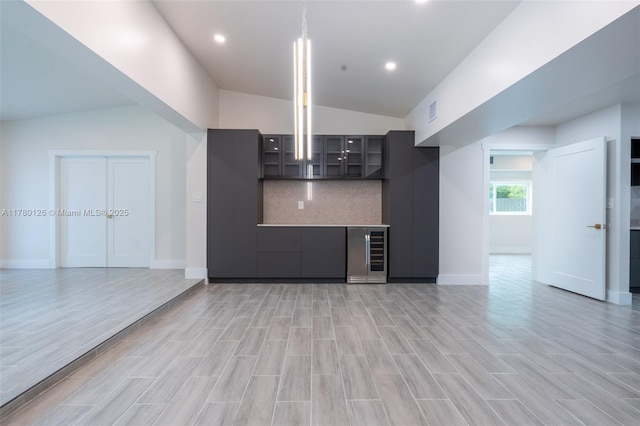 kitchen with glass insert cabinets, wine cooler, backsplash, light wood-style flooring, and lofted ceiling