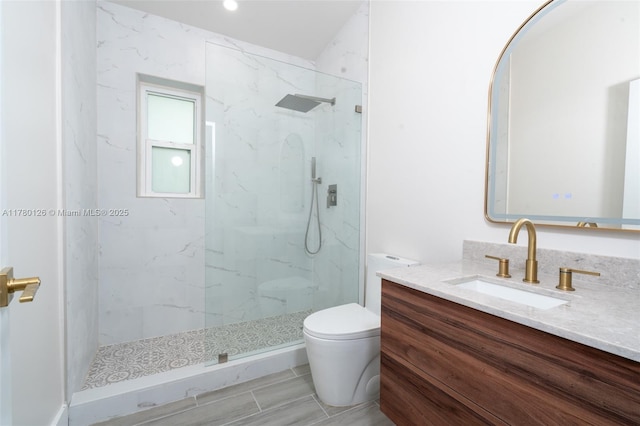 full bath with vanity, a marble finish shower, and toilet