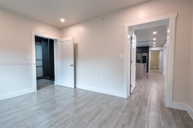 unfurnished room with baseboards, wood finish floors, and recessed lighting