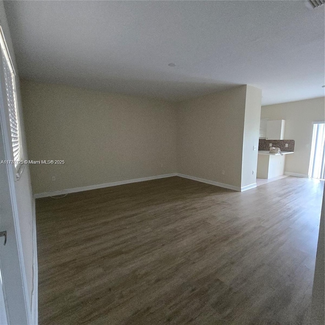 unfurnished room with dark wood-type flooring and baseboards
