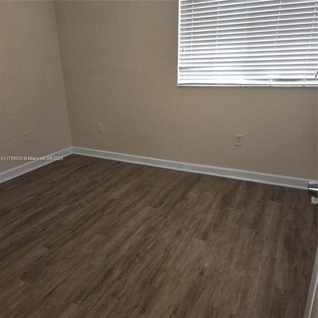 empty room with baseboards and dark wood finished floors