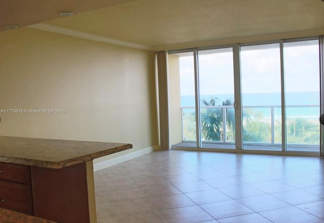 spare room featuring crown molding, baseboards, floor to ceiling windows, and light tile patterned floors