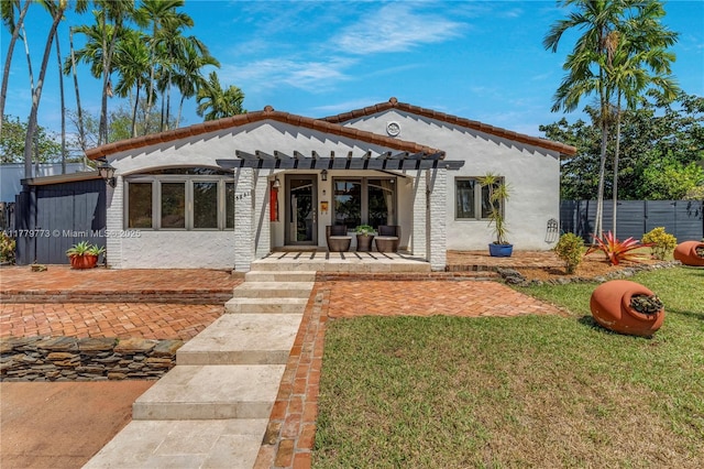 view of front facade with a front yard, stucco siding, and fence