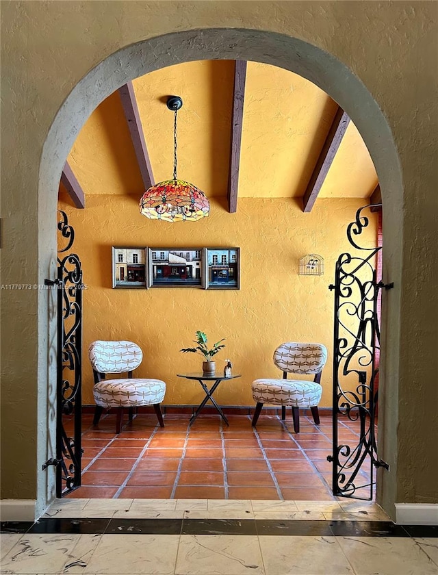 sitting room with beam ceiling, a textured wall, and arched walkways