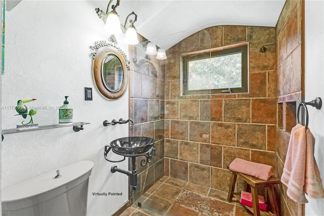 full bath with toilet, vaulted ceiling, and tiled shower