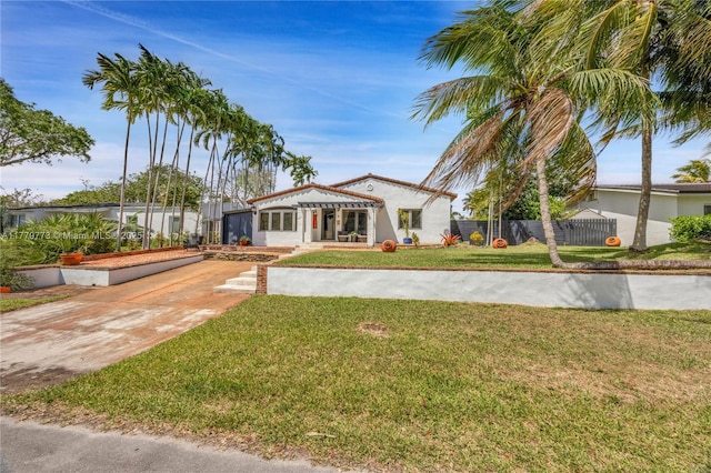 mediterranean / spanish house with fence, a front yard, and concrete driveway