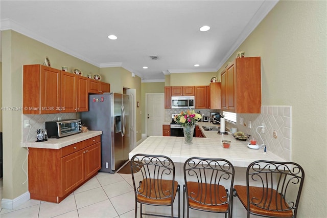 kitchen featuring a kitchen bar, a peninsula, ornamental molding, stainless steel appliances, and a toaster