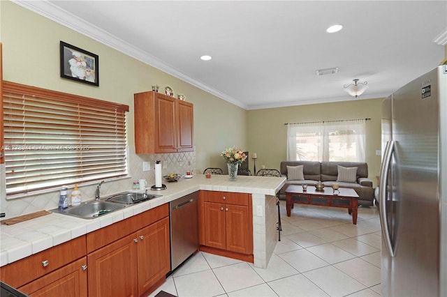 kitchen featuring a sink, open floor plan, a peninsula, stainless steel appliances, and decorative backsplash