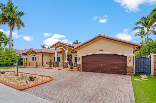 3663 SW 150th Ct, Miami, FL 33185 - mediterranean / spanish-style house featuring a gate, stucco siding, decorative driveway, an attached garage, and stone siding
