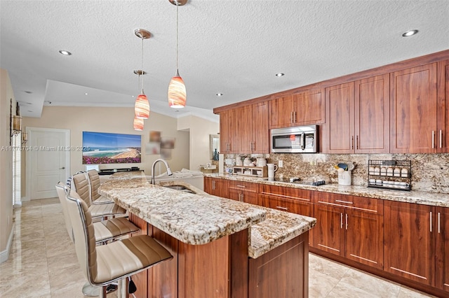 3663 SW 150th Ct, Miami, FL 33185 - kitchen featuring stainless steel microwave, tasteful backsplash, light stone counters, a breakfast bar, and a kitchen island with sink