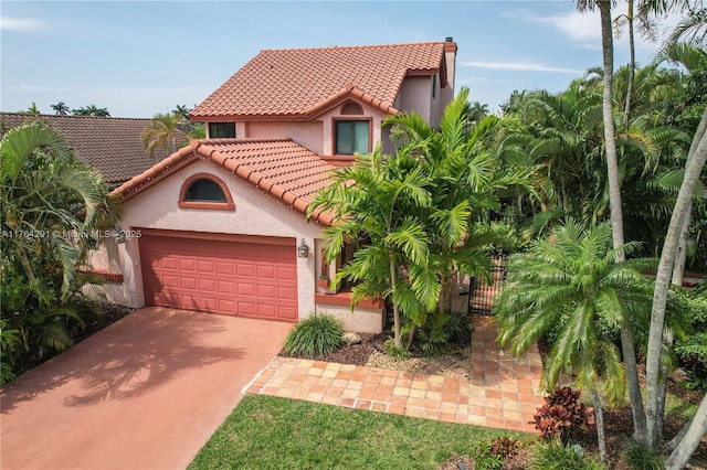mediterranean / spanish-style home featuring a tiled roof, an attached garage, concrete driveway, stucco siding, and a gate