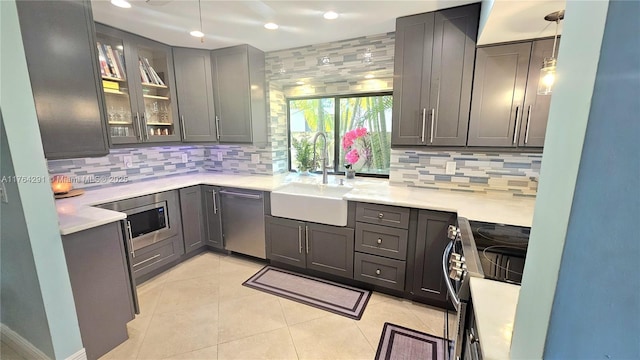 kitchen with a sink, light countertops, appliances with stainless steel finishes, gray cabinets, and decorative backsplash