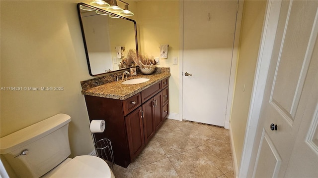 half bathroom featuring toilet, tile patterned flooring, baseboards, and vanity