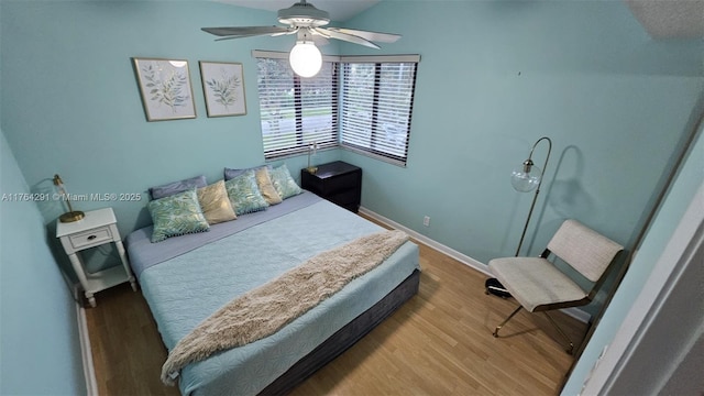 bedroom featuring baseboards, ceiling fan, wood finished floors, and lofted ceiling