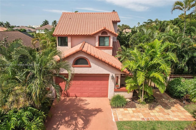 mediterranean / spanish-style house featuring an attached garage, concrete driveway, stucco siding, and a tile roof