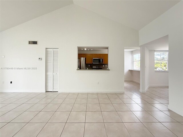 4756 NW 97th Ct Unit 79, Doral, FL 33178 - unfurnished living room featuring visible vents, baseboards, high vaulted ceiling, and light tile patterned floors