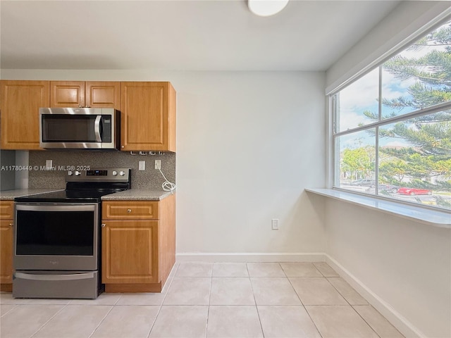 4756 NW 97th Ct Unit 79, Doral, FL 33178 - kitchen featuring light tile patterned floors, baseboards, brown cabinetry, stainless steel appliances, and decorative backsplash
