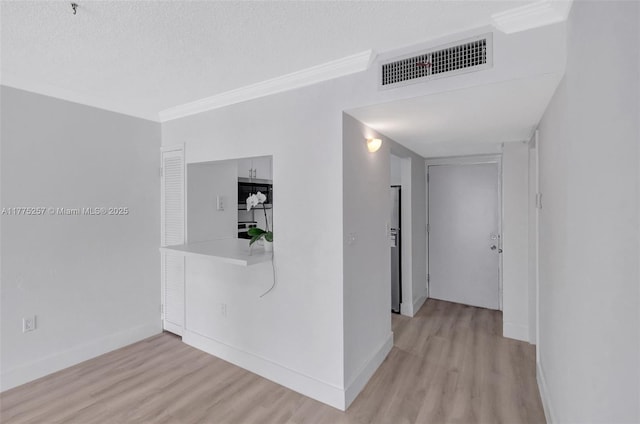 corridor featuring ornamental molding, light wood finished floors, visible vents, and baseboards