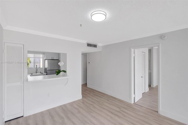 unfurnished living room with a sink, crown molding, visible vents, and wood finished floors