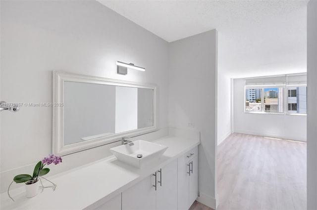 bathroom with wood finished floors, vanity, and baseboards