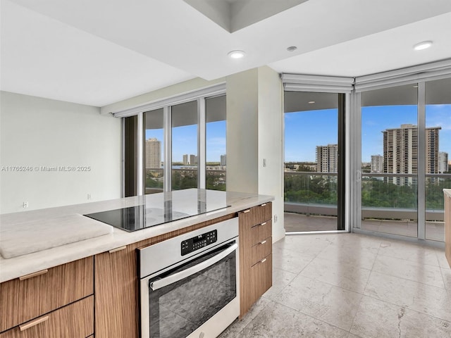 7000 Island Blvd Unit 1208, Aventura, FL 33160 - kitchen with oven, black electric cooktop, a view of skyline, brown cabinetry, and modern cabinets