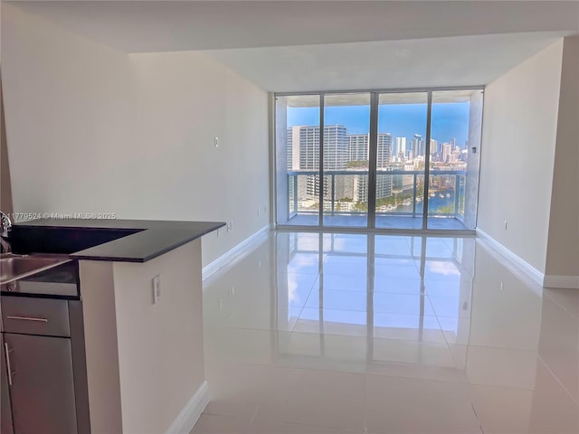 interior space featuring a view of city, dark countertops, light tile patterned floors, and expansive windows