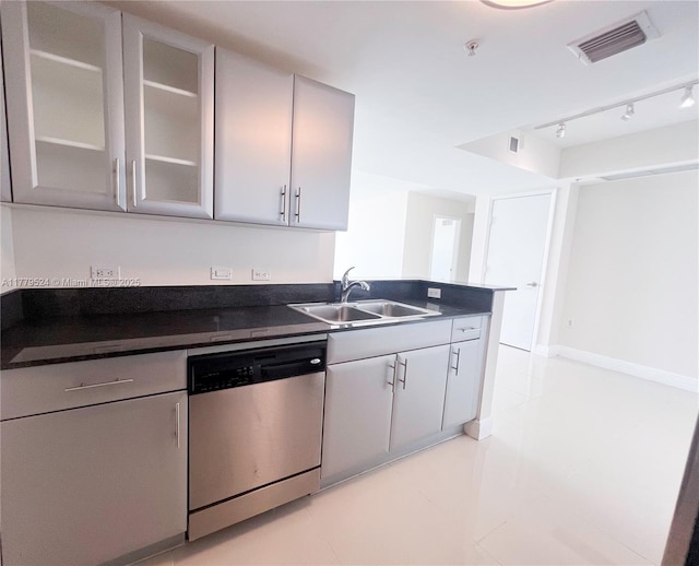 kitchen with glass insert cabinets, dark countertops, visible vents, stainless steel dishwasher, and a sink