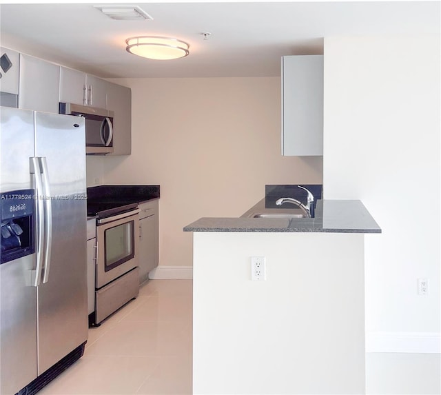 kitchen with gray cabinets, a peninsula, visible vents, appliances with stainless steel finishes, and a sink