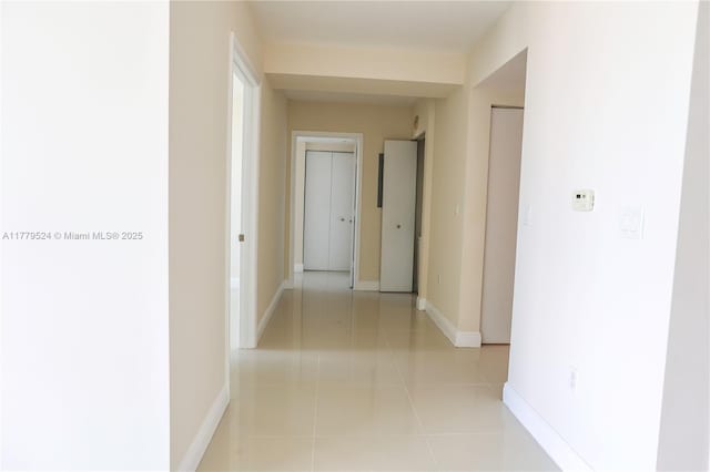 hallway featuring light tile patterned floors and baseboards