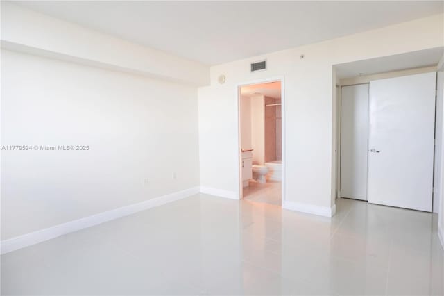 unfurnished bedroom featuring ensuite bath, visible vents, baseboards, and light tile patterned flooring