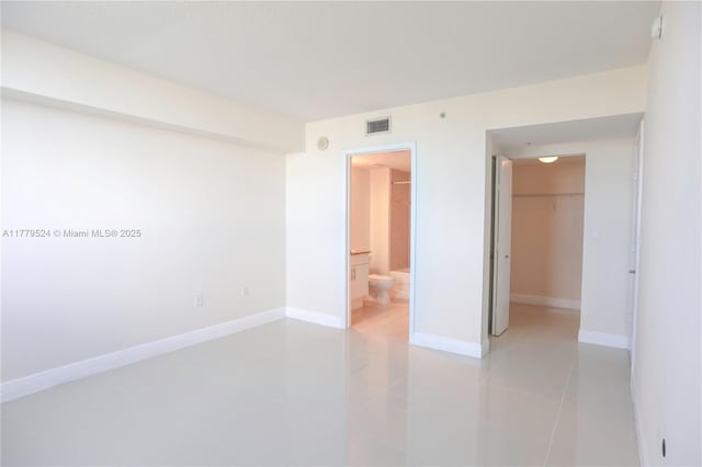 unfurnished bedroom featuring a closet, baseboards, connected bathroom, a walk in closet, and visible vents