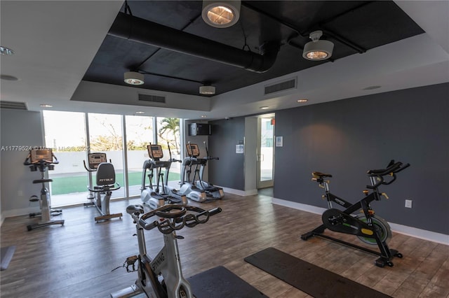 gym with wood finished floors, baseboards, and visible vents