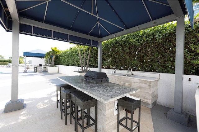 view of patio with outdoor wet bar, a grill, a sink, exterior kitchen, and a gazebo