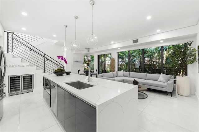 2679 NE 8th Ave, Wilton Manors, FL 33334 - kitchen featuring a sink, modern cabinets, light tile patterned floors, a kitchen island with sink, and light stone counters