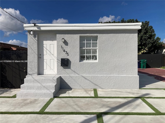 doorway to property with fence and stucco siding