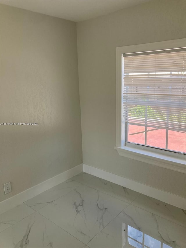 empty room featuring baseboards and marble finish floor