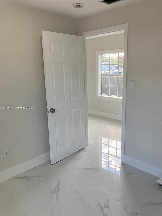 spare room with baseboards and marble finish floor