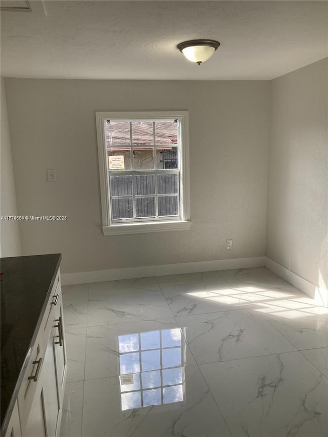 empty room featuring marble finish floor and baseboards