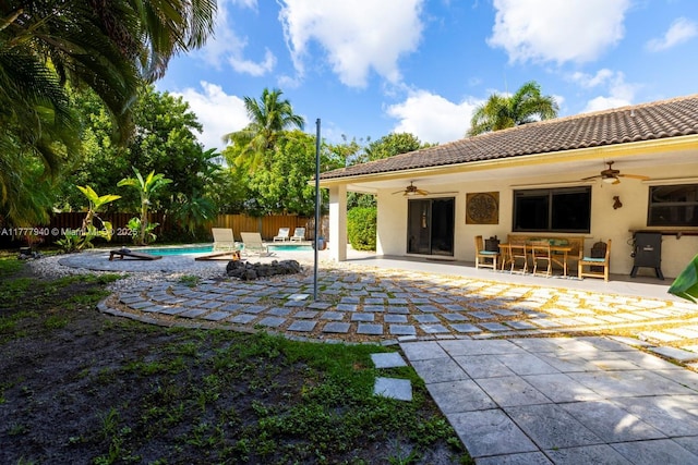 back of house with a fenced backyard, ceiling fan, stucco siding, and a tiled roof