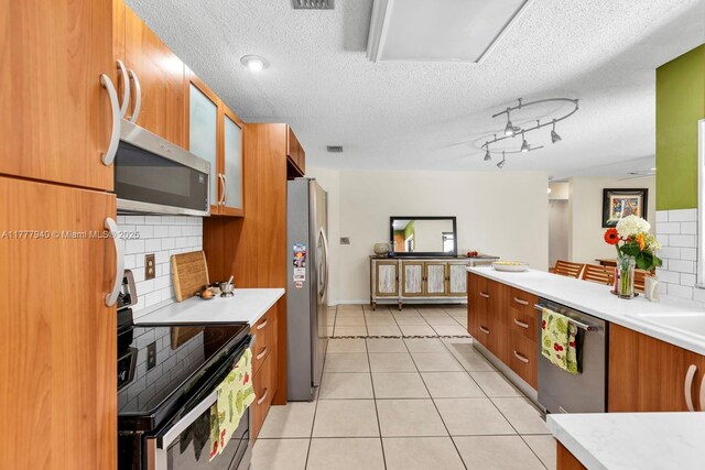 14811 Archerhall St, Davie, FL 33331 - kitchen with stainless steel appliances, brown cabinets, decorative backsplash, light countertops, and a textured ceiling