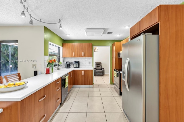 kitchen featuring stainless steel appliances, visible vents, brown cabinetry, and a healthy amount of sunlight